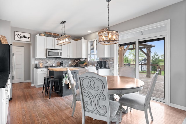 dining space featuring an inviting chandelier, baseboards, light wood finished floors, and recessed lighting