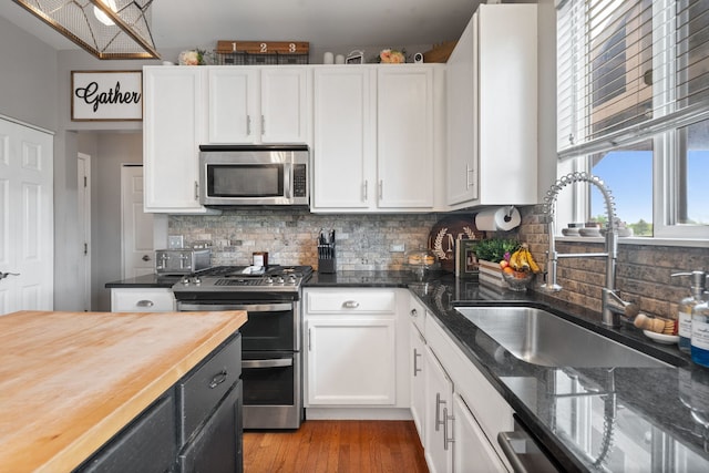 kitchen featuring a sink, butcher block countertops, decorative backsplash, and appliances with stainless steel finishes