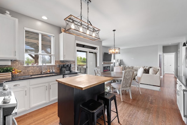 kitchen with white cabinetry, wooden counters, open floor plan, and a sink