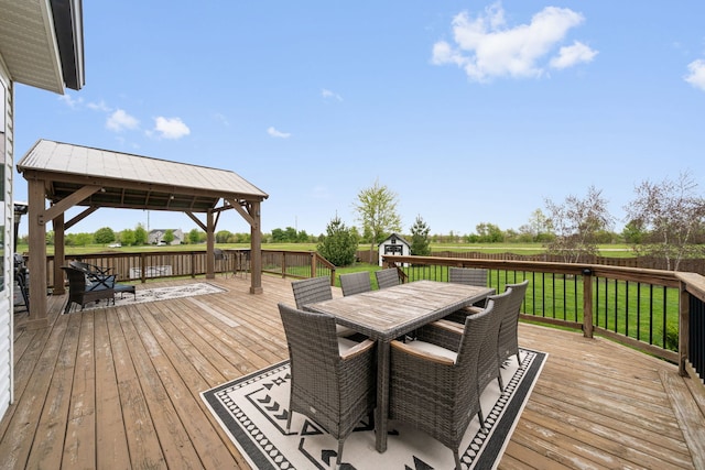 wooden terrace featuring a yard, outdoor dining space, an outdoor structure, a gazebo, and a storage shed