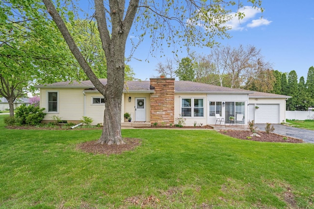 ranch-style home with a chimney, a front lawn, aphalt driveway, and a garage