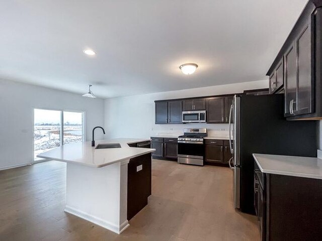 1587 Glenbrooke Ln, New Lenox, IL 60451 - kitchen with stainless steel appliances, a sink, light wood-style flooring, a kitchen island with sink, and light countertops