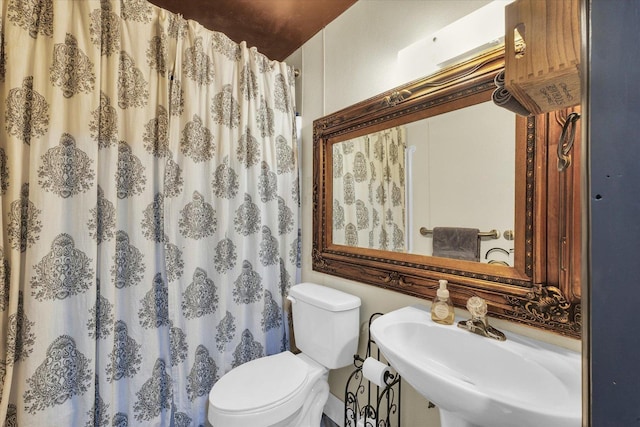 bathroom featuring a sink, curtained shower, and toilet