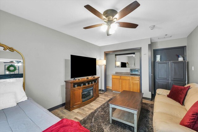 living area featuring light wood finished floors, a toaster, visible vents, baseboards, and ceiling fan