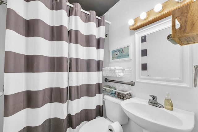 bathroom featuring toilet, curtained shower, and a sink