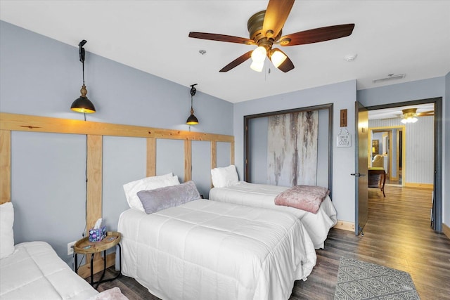 bedroom with a ceiling fan, visible vents, wood finished floors, and baseboards