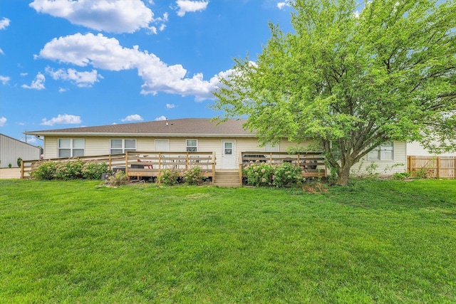 back of house with a deck, fence, and a lawn