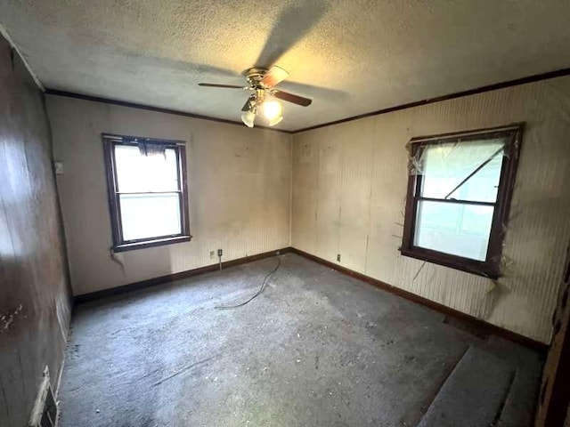 empty room featuring a textured ceiling, a ceiling fan, and baseboards