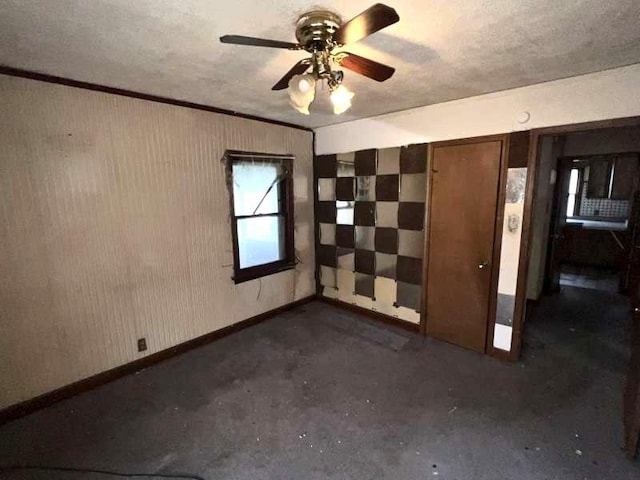 spare room with a ceiling fan, concrete floors, a textured ceiling, and baseboards