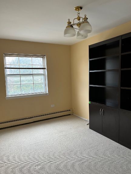725 Grove Dr Unit 209, Buffalo Grove, IL 60089 - carpeted spare room with a baseboard radiator and an inviting chandelier