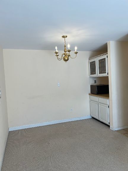 725 Grove Dr Unit 209, Buffalo Grove, IL 60089 - unfurnished room with a chandelier, baseboards, and light carpet