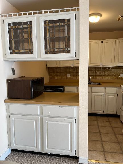 725 Grove Dr Unit 209, Buffalo Grove, IL 60089 - kitchen featuring white cabinetry, black microwave, and decorative backsplash