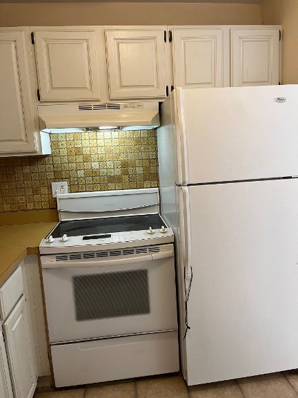 725 Grove Dr Unit 209, Buffalo Grove, IL 60089 - kitchen with under cabinet range hood, decorative backsplash, white cabinets, and white appliances