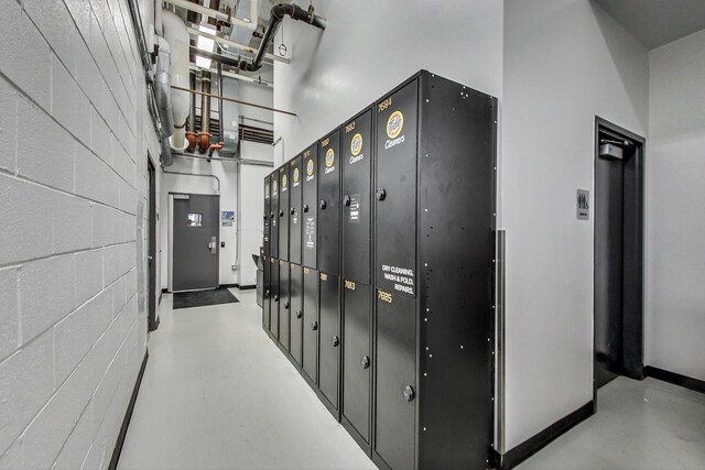 235 W Van Buren St Unit 3414, Chicago, IL 60607 - hallway featuring concrete block wall, concrete flooring, baseboards, and a towering ceiling