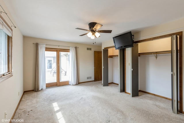 unfurnished bedroom with light carpet, two closets, access to outside, and baseboards