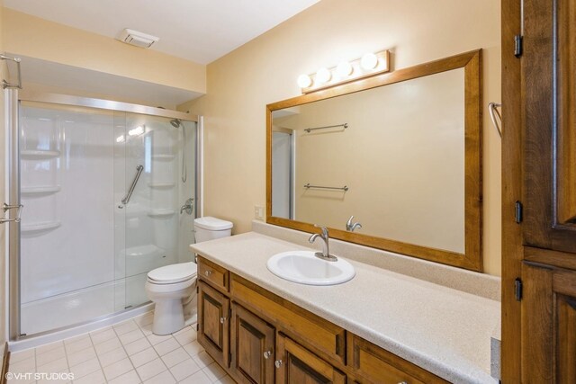 full bathroom featuring toilet, tile patterned flooring, a stall shower, and vanity