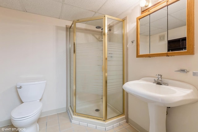 bathroom with toilet, a shower stall, baseboards, and tile patterned flooring