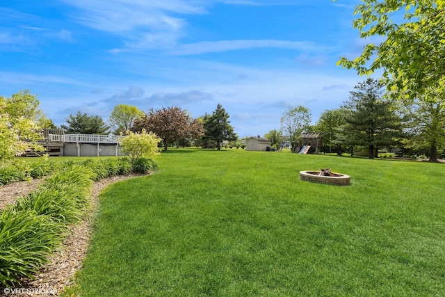 view of green lawn with a fire pit