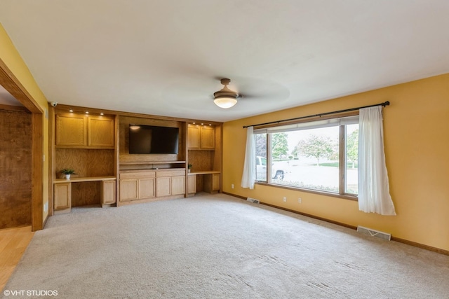 unfurnished living room with baseboards, light colored carpet, and ceiling fan