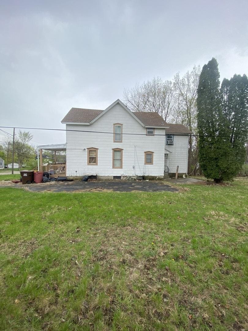 back of house with a yard and a shingled roof