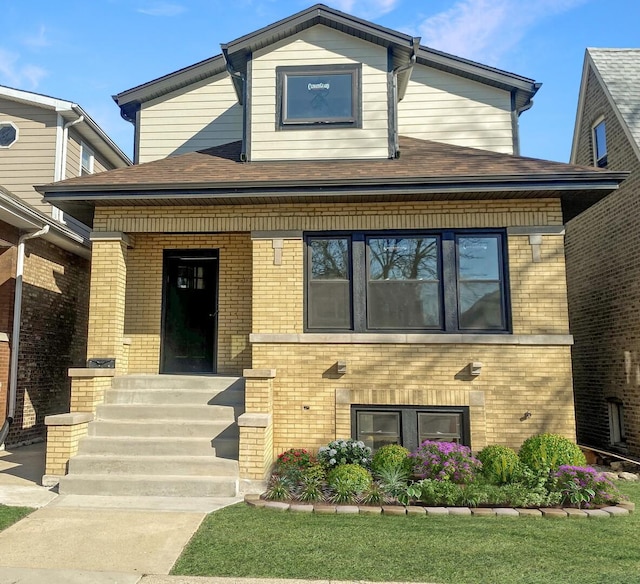 view of front facade with covered porch, a shingled roof, and brick siding