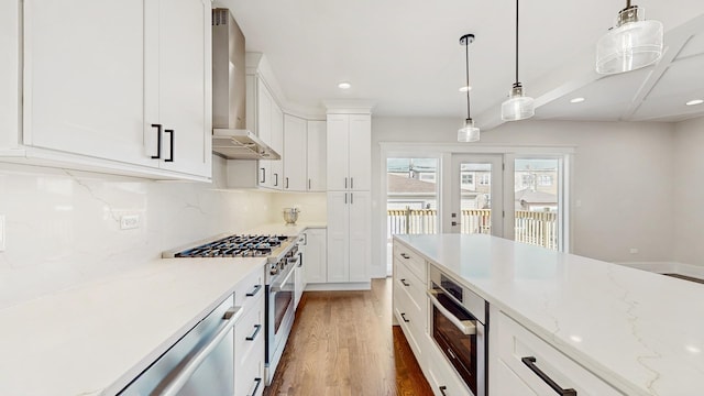 kitchen featuring light wood finished floors, wall chimney range hood, recessed lighting, and appliances with stainless steel finishes