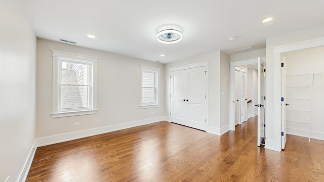 unfurnished bedroom with baseboards, recessed lighting, visible vents, and wood finished floors