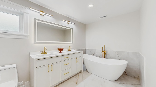 bathroom featuring marble finish floor, a freestanding tub, visible vents, and a sink