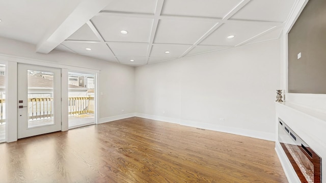 unfurnished living room featuring baseboards, recessed lighting, coffered ceiling, and wood finished floors