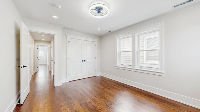 unfurnished bedroom with a closet, visible vents, recessed lighting, dark wood-style flooring, and baseboards