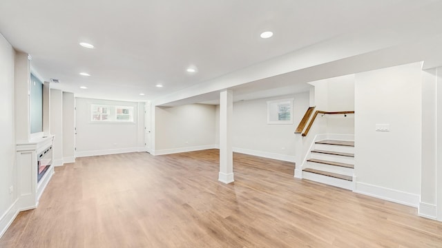 basement featuring stairs, baseboards, light wood-style flooring, and recessed lighting