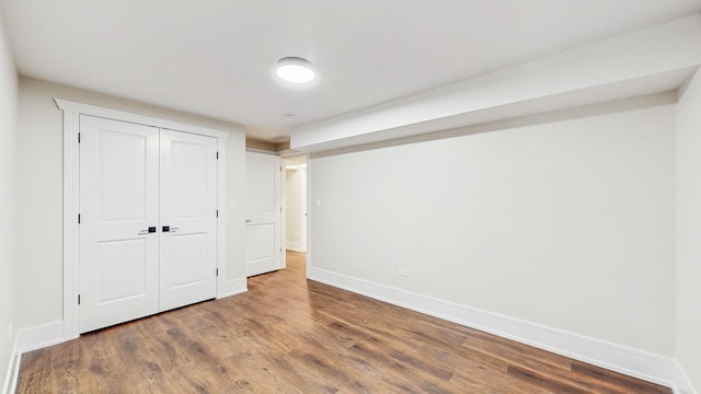 unfurnished bedroom featuring a closet, wood finished floors, and baseboards