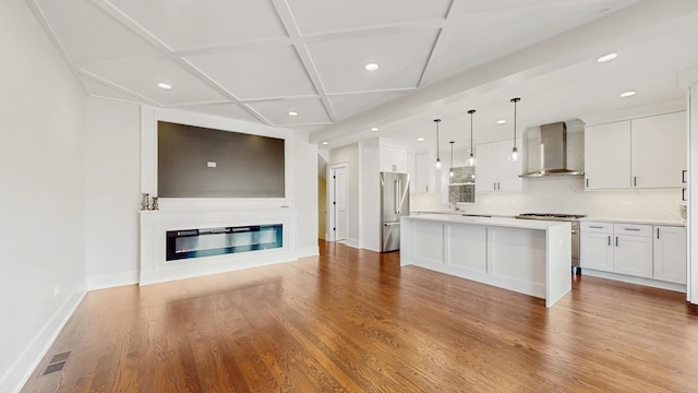 kitchen with coffered ceiling, high quality appliances, white cabinetry, wall chimney range hood, and recessed lighting