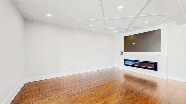 unfurnished living room featuring wood finished floors, recessed lighting, coffered ceiling, baseboards, and a glass covered fireplace
