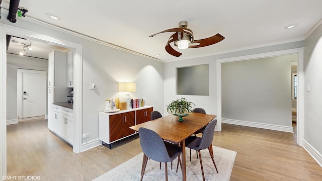 dining room with light wood-type flooring, ornamental molding, and ceiling fan