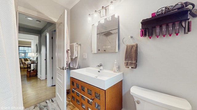 bathroom with toilet, wood finished floors, and vanity
