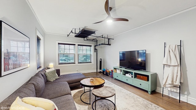 living area featuring ornamental molding, baseboards, a ceiling fan, and wood finished floors