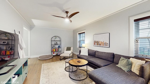 living area featuring crown molding, baseboards, wood finished floors, and a ceiling fan
