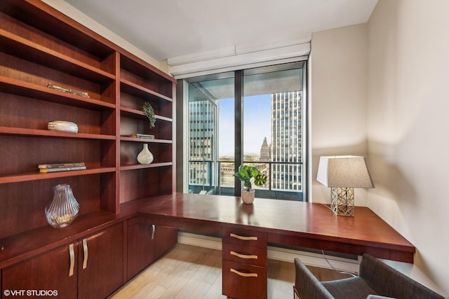 unfurnished office featuring built in study area and light wood-style floors