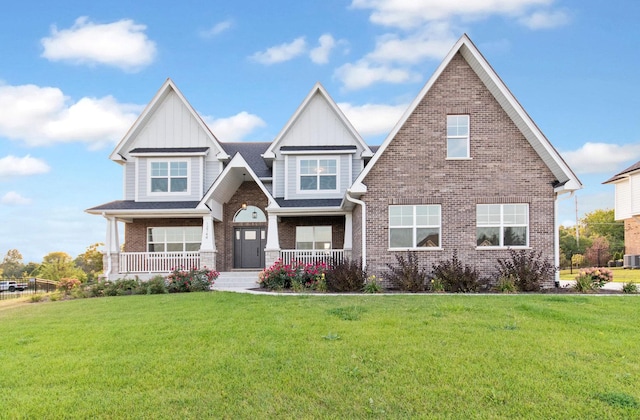 craftsman-style home with brick siding, board and batten siding, a front yard, and a porch