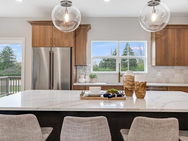 kitchen with backsplash, high end fridge, and brown cabinetry