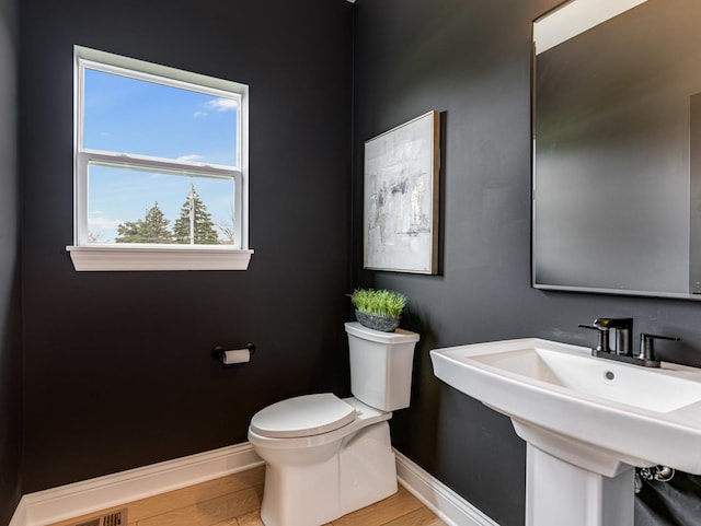 bathroom featuring a sink, toilet, baseboards, and wood finished floors