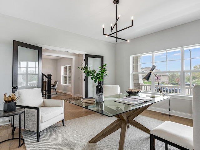 dining space with an inviting chandelier, baseboards, wood finished floors, and a healthy amount of sunlight