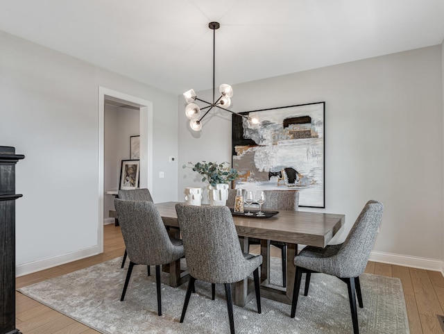 dining area with baseboards, an inviting chandelier, and wood finished floors