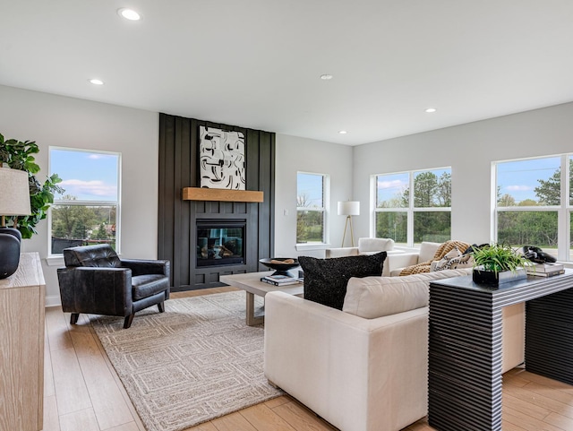 living area with recessed lighting, light wood-style floors, a healthy amount of sunlight, and a large fireplace