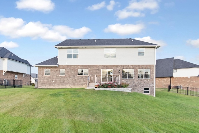 rear view of property featuring fence, brick siding, and a lawn