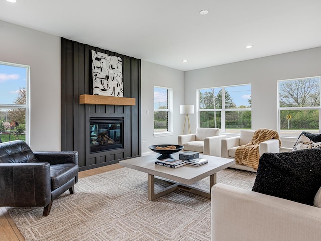 living area with recessed lighting, a large fireplace, and light wood-type flooring