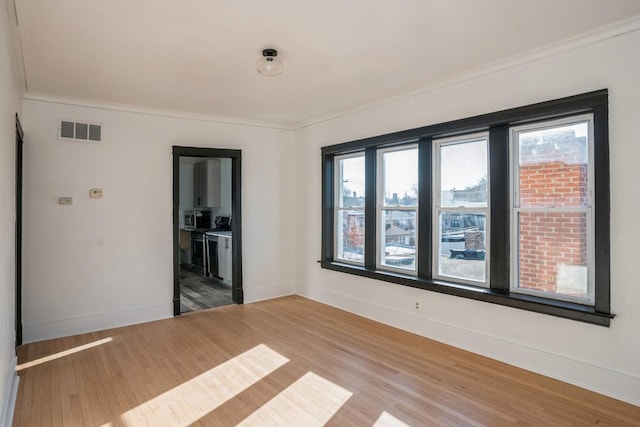 spare room with ornamental molding, light wood-type flooring, and baseboards