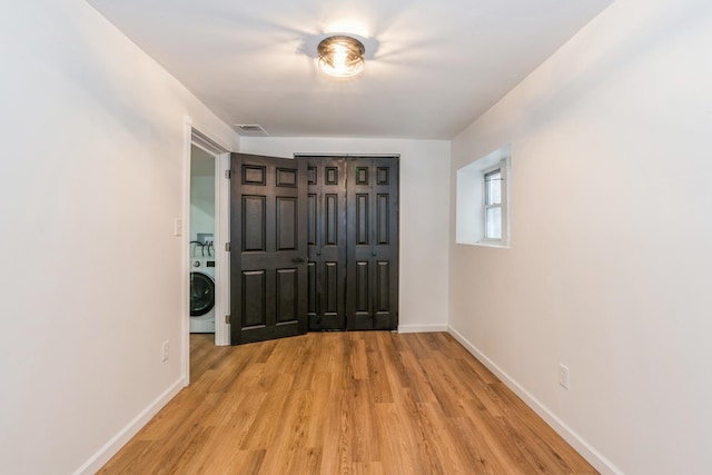 hall featuring washer / clothes dryer, light wood-style flooring, and baseboards