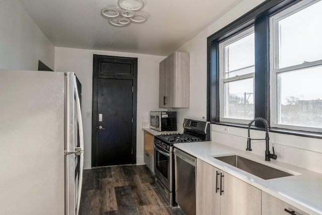 kitchen featuring stainless steel appliances, a sink, light countertops, dark wood-style flooring, and light brown cabinets